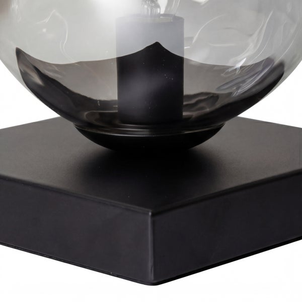 Tischleuchte mit schwarzem quadratischem Metallsockel und runder Glaskugel aus Rauchglas.