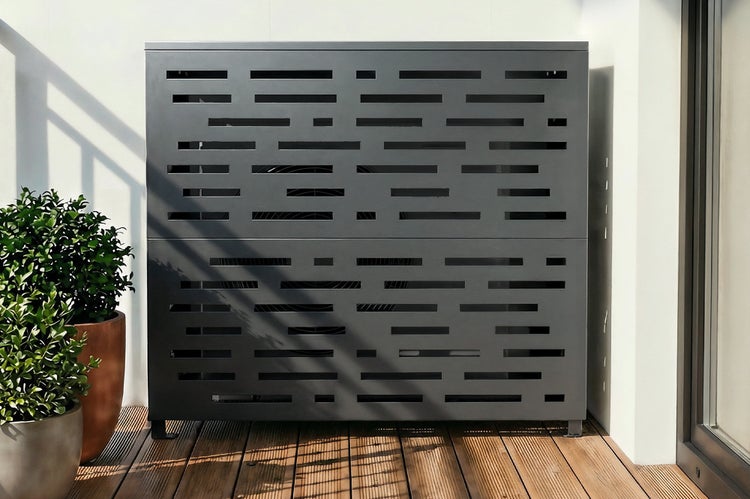 Moderne Metallverkleidung für Klimaanlagen oder Wärmepumpen mit horizontalen Aussparungen auf einer Terrasse mit Holzdeck.