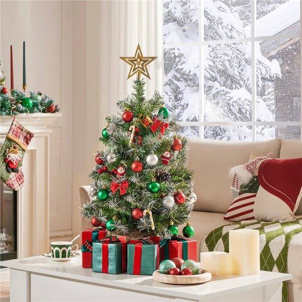 Dekorierter Weihnachtsbaum mit Sternspitze, Geschenken und Dekorationen in einem Wohnzimmer mit Sofa und Kamin.
