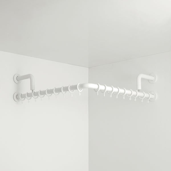 Weiße L-förmige Duschvorhangstange mit Vorhangringen, montiert in einer Wandecke.