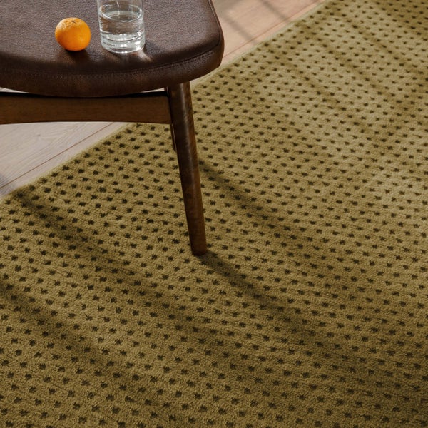 Strukturierter Teppich mit regelmäßigem Punktmuster auf Holzfußboden neben einem Stuhlbein aus Holz.