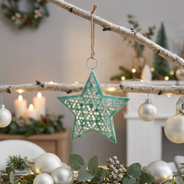 Weihnachtsbaumschmuck in Sternform mit Lochmuster hängend an einem Ast zur Dekoration