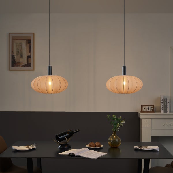 Zwei ovale Pendelleuchten mit beigen Textilschirmen hängen über einem dunklen Esstisch in einem modern eingerichteten Raum.