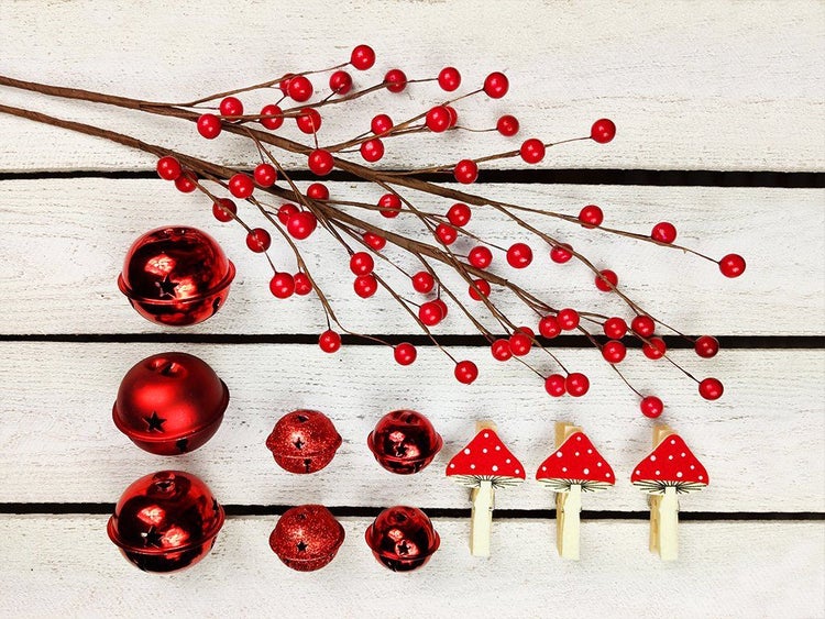 Weihnachtliche Dekorationsartikel bestehend aus Zweigen mit Beeren, verschieden großen Glocken und Holzklammern mit Fliegenpilzmotiven