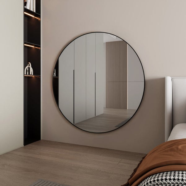 Runder Spiegel an einer Wand im Schlafzimmer, der den Raum optisch vergrößert.