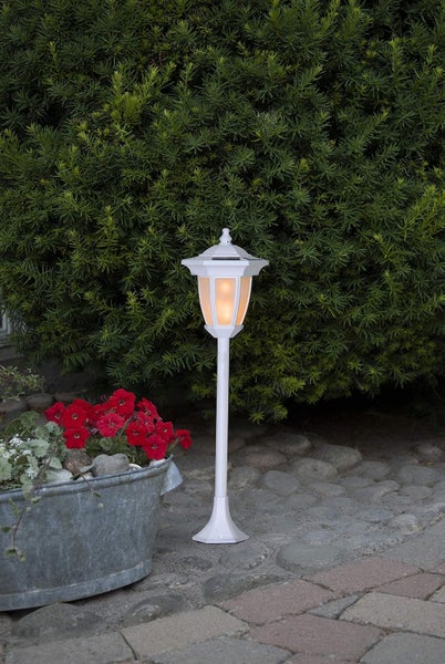 Weiße Gartenlampe mit Solarenergie neben einem Blumenkasten im Außenbereich