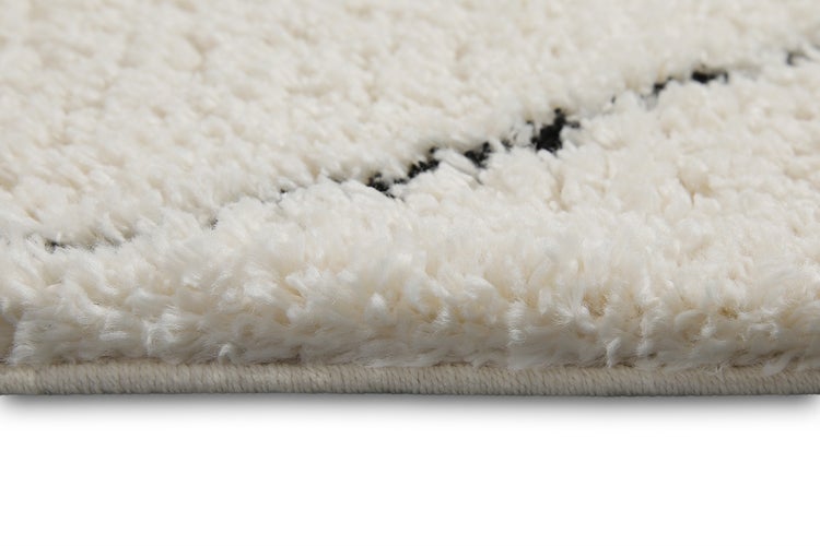 Hochflor-Teppich in Weiß mit schwarzen Streifen, weiche Textur, Detailansicht der Kante.
