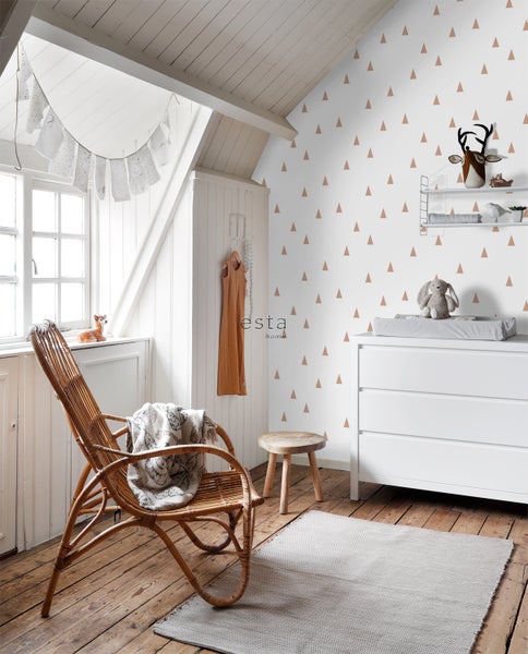 Kinderzimmer mit Wickelkommode, Rattansessel und Wandaufklebern mit Dreiecksmuster.