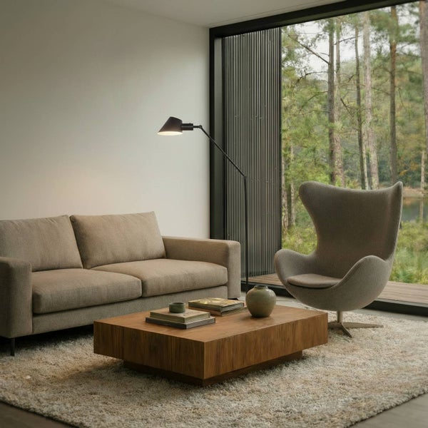 Wohnzimmer mit Sofa, Sessel, Stehlampe und Couchtisch auf Teppich