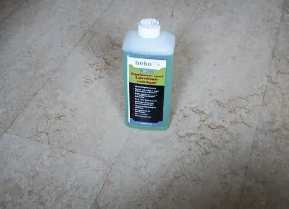 Beko Parkett- und Laminatreiniger in einer Kunststoffflasche auf einem Steinboden.