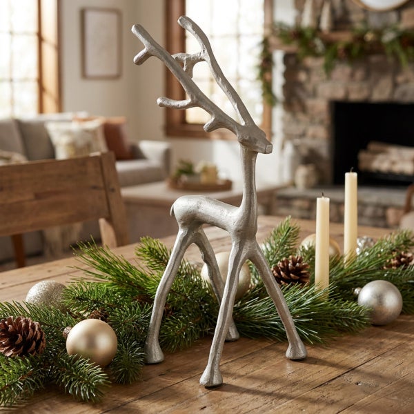 Dekorative Weihnachtsfigur in Form eines Rentiers aus Metall auf einem Holztisch mit Tannenzweigen, Kerzen und Weihnachtskugeln dekoriert.