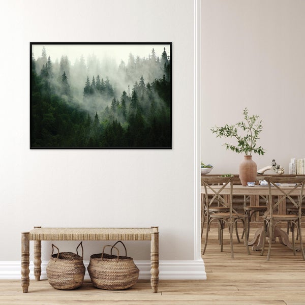 Wandbild mit Waldmotiv in schwarzem Rahmen über einer Sitzbank mit zwei Rattankörben in einem hell eingerichteten Wohnzimmer.