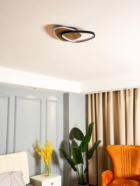 Moderne Deckenleuchte mit Holz- und schwarzen Elementen in einem hellen Wohnzimmer mit grauer Wandtäfelung, orangefarbenem Sessel und Zimmerpflanze.