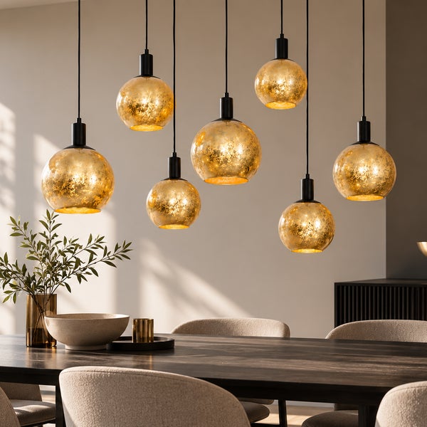 Moderne Hängeleuchte mit sieben kugelartigen Glasköpfen in Metallfassung über einem Esstisch in einem hellen und stilvoll eingerichteten Raum.