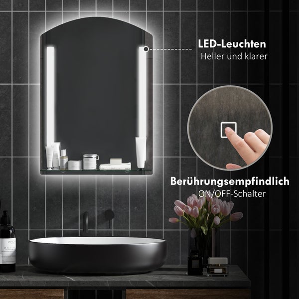 Moderner Badezimmerspiegel mit Bogenform, LED-Beleuchtung, Glasablage und Touch-Schalter über einem schwarzen Waschbecken vor dunklen Wandfliesen.