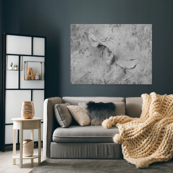 Modernes Wohnzimmer mit großem Leinwandbild einer Frau mit Hut über einem grauen Sofa mit grob gestrickter Decke.