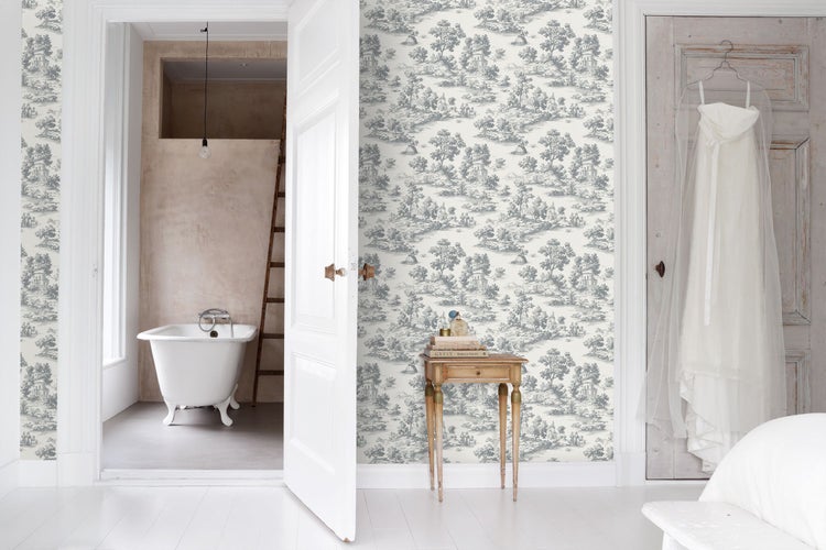 Heller Raum mit Vliestapete im Toile-de-Jouy-Stil mit Landschaftsmuster, offenem Durchgang zu einem Badezimmer mit freistehender Badewanne.