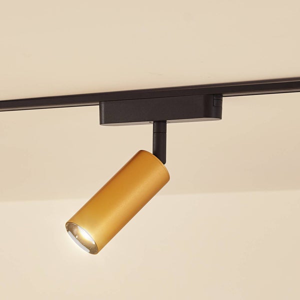 Moderner, zylindrischer Schienensystem-Strahler in Gold an einer schwarzen Schiene, Metall, eingeschaltetes Licht.