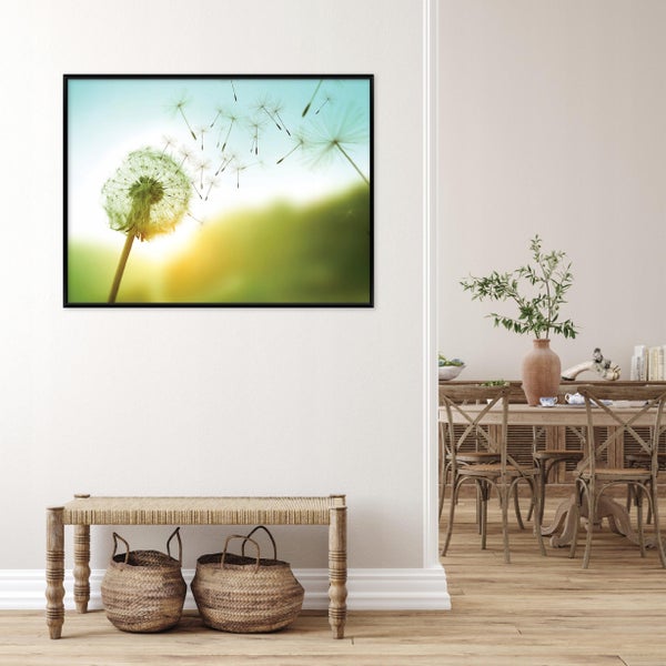 Wandbild Pusteblume mit schwarzem Rahmen in einem hellen Wohnraum mit Holztisch und Weidenkörben.