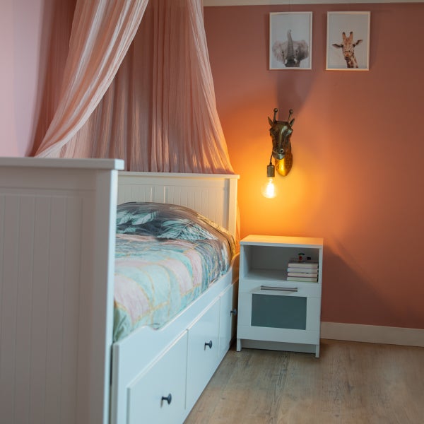 Kinderzimmer mit weißem Bett, Nachttisch und Giraffen-Wandleuchte