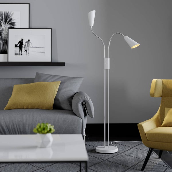 Stehleuchte mit zwei Lampenarmen in einem Wohnzimmer mit Sofa und Sessel.