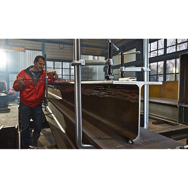 Metallarbeiter mit Wasserwaage und Schraubzwingen an einem Stahlträger