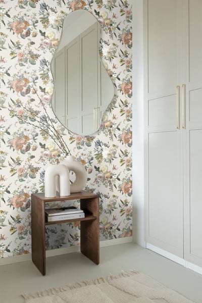 Dekoratives Zimmer mit Blumentapete, Spiegel, Beistelltisch und Teppich.