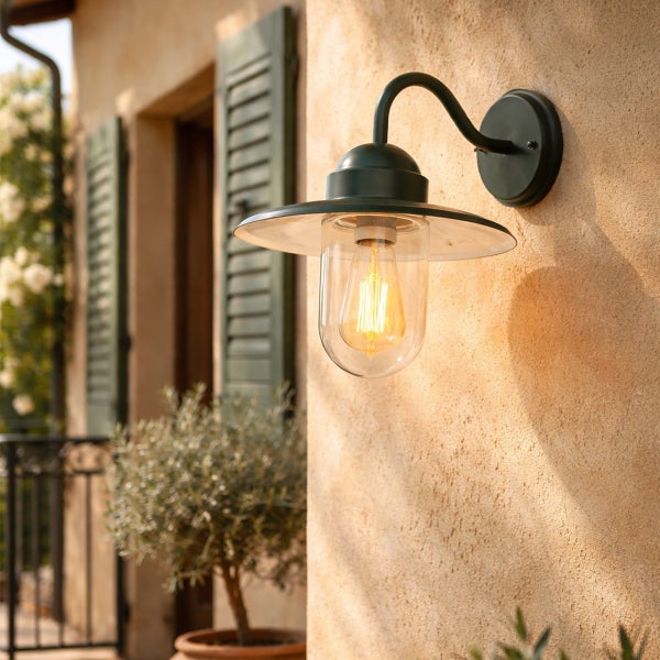 Rustikale Außenwandleuchte im Vintage-Stil mit gebogenem Arm, flachem Schirm und Glaskolben, montiert an einer Fassade.