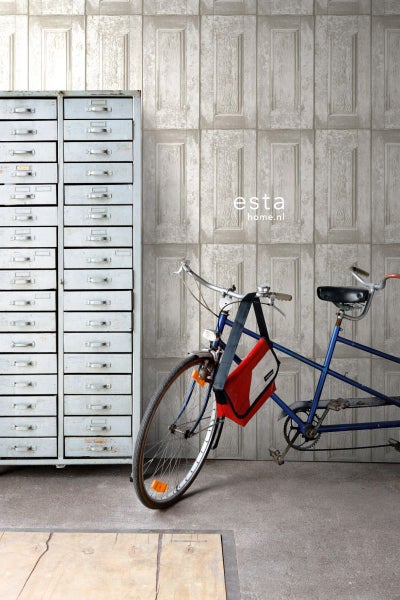 Szene mit einer Tapete in Türpaneeloptik, einem Metallschrank mit Schubladen und einem Fahrrad