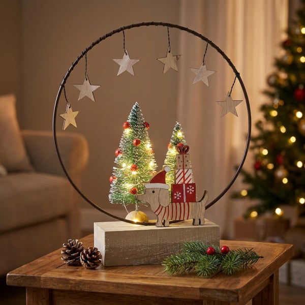 Beleuchtete Weihnachtsdekoration mit Metallring, Holzfiguren von Hund und Geschenken, kleinen Tannenbäumen und hängenden Holzsternen auf Holzsockel.