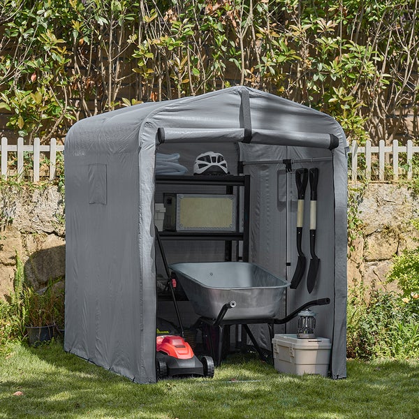 Graues Gartengerätehaus mit Gartengeräten im Rasen