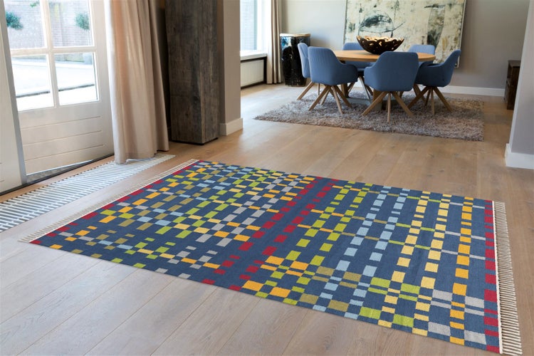 Wohnzimmer mit modernem Teppich mit geometrischem Karomuster und Fransen auf Holzboden in einem hellen und großzügigen Wohnbereich.