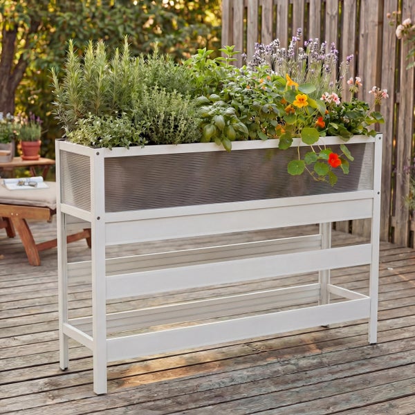 Weißes Hochbeet auf einer Holzterrasse, bepflanzt mit Kräutern wie Rosmarin und Basilikum sowie bunten Blumen.