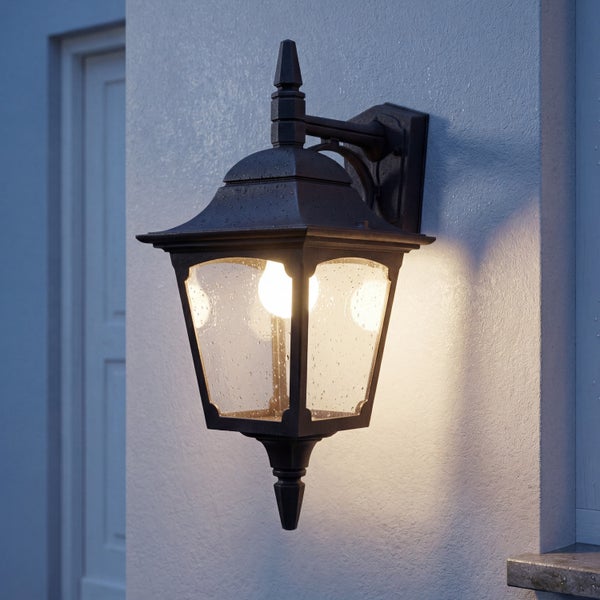 Klassische Außenwandleuchte im Laternen-Design mit warmem Licht und Wassertropfen auf dem Glas.