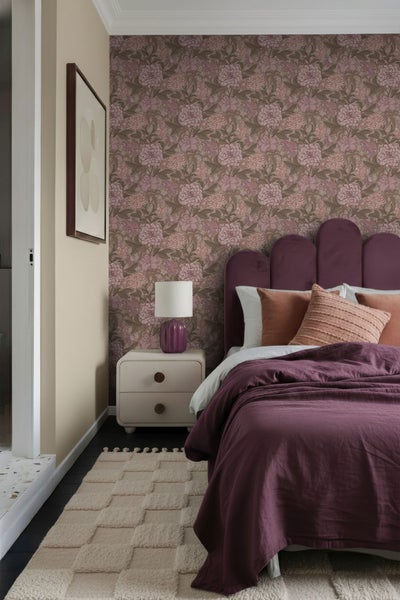 Schlafzimmer mit Bett, Nachttisch, Lampe, Teppich und floraler Tapete für eine gemütliche Atmosphäre