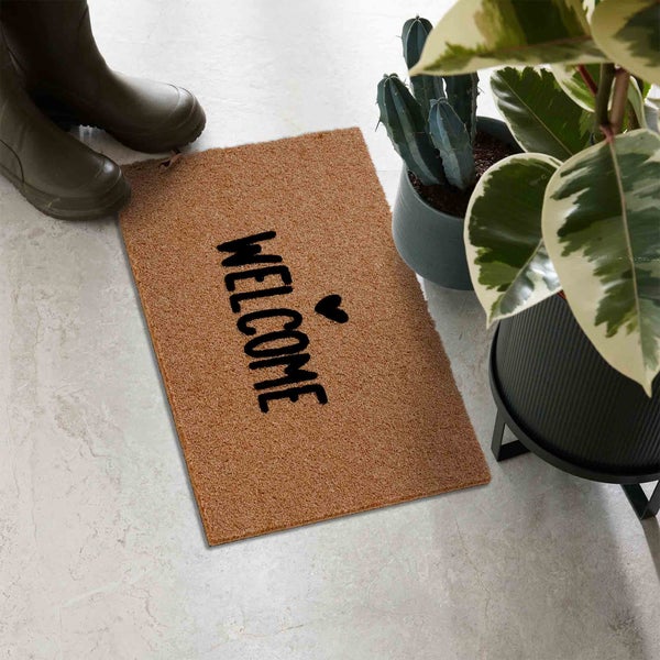 Fußmatte mit der Aufschrift Willkommen, Gummistiefel und Pflanzen im Topf