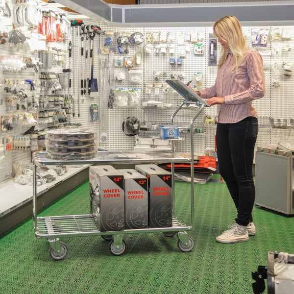 Kundin mit Einkaufswagen im Baumarkt, der mit Radkappen und anderen Artikeln beladen ist