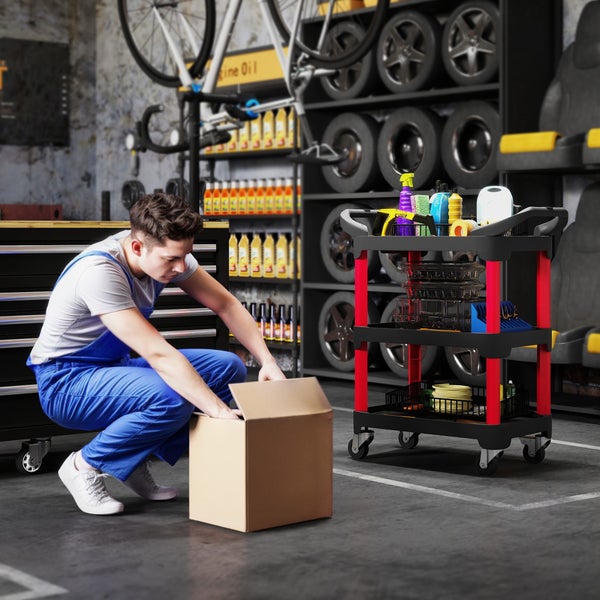 Werkstatt mit Mechaniker, der eine Box öffnet, und einem Werkzeugwagen mit drei Regalen