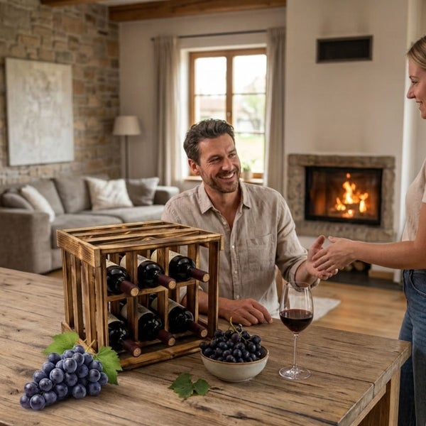 Ein rustikales Weinregal aus Holz auf einem Holztisch in einem Wohnzimmer mit Kamin, im Hintergrund ein glückliches Paar.