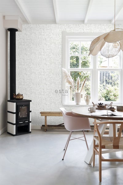 Heller Raum mit Ofen, Esstisch und gemusterter Tapete