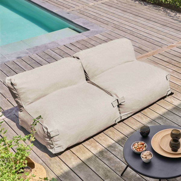 Zweisitzer Outdoor Sitzsack Sofa auf einer Holzterrasse neben einem Pool mit einem kleinen Beistelltisch und Snacks.