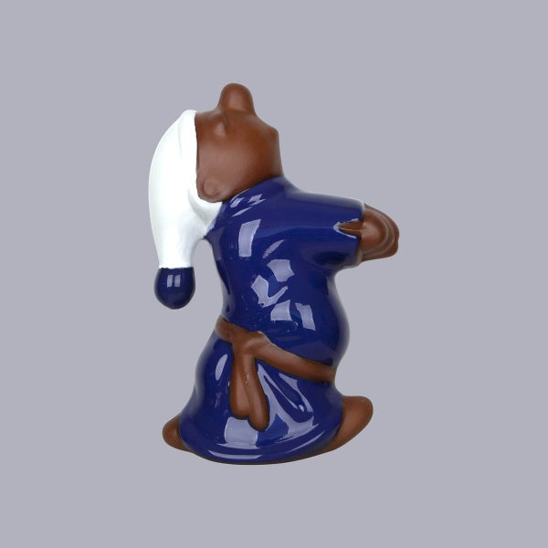 Dekorative Keramikfigur eines sitzenden Mönchs mit weißer Schlafmütze und blauem Gewand.