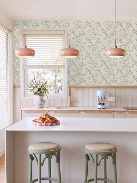 Vliestapete mit floralem Muster in Beige und Braun, kombiniert mit einem Wandspiegel und Vasen auf einem Marmortisch.
