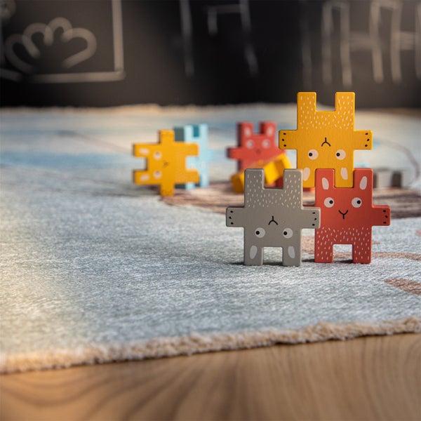 Stapelbare Holzfiguren in Form von Hasen auf einem Kinderteppich für kreatives Spielen.