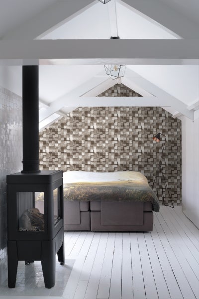 Heller Dachboden mit Bett, Kamin und Holzwandverkleidung für eine gemütliche Atmosphäre.