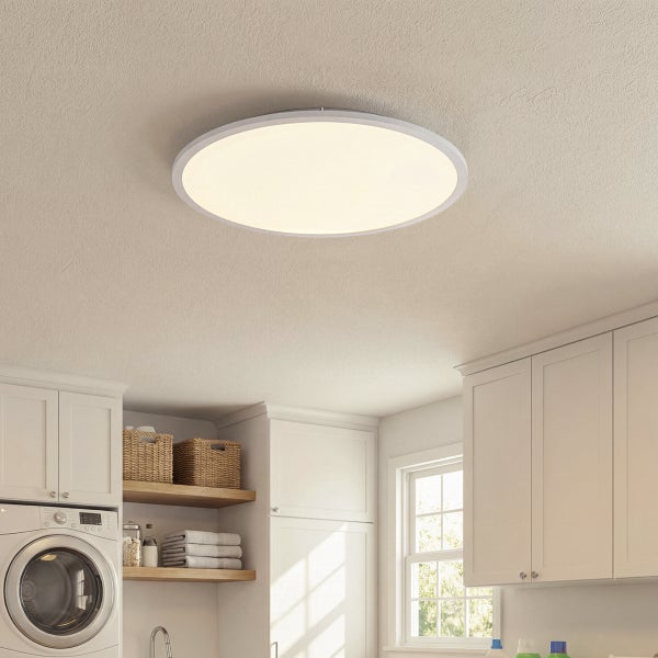 Rundes flaches LED-Panel an einer Decke in einem hellen Hauswirtschaftsraum mit Schränken und Waschmaschine.