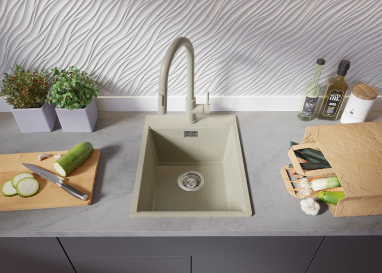 Küchenspüle mit Armatur auf einer Arbeitsplatte mit Gemüse und Kräutern