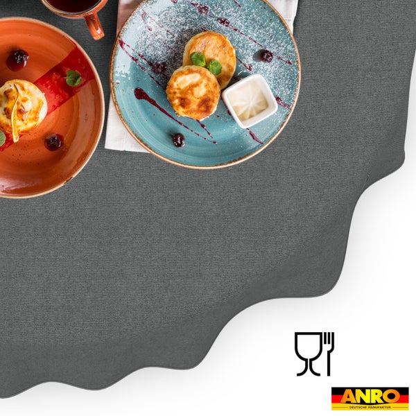 Dunkelgraue, strukturierte Tischdecke mit Wellenrand, Tellern und Speisen, lebensmittelecht, ANRO Deutsche Manufaktur Logo.