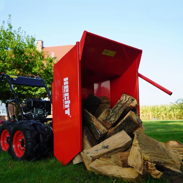 Ein roter Hecht Motordumper entlädt gespaltenes Brennholz auf einer Rasenfläche im Garten.