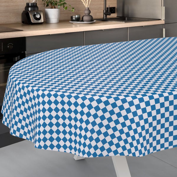 Ovale Tischdecke mit blau-weißem Karomuster auf einem Tisch in einer hellen, organisierten Küche mit moderner Küchenzeile und Spülbecken.